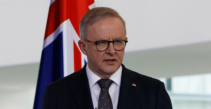 Australian Prime Minister Anthony Albanese delivers speech in front of Australian flag (future made in australia)