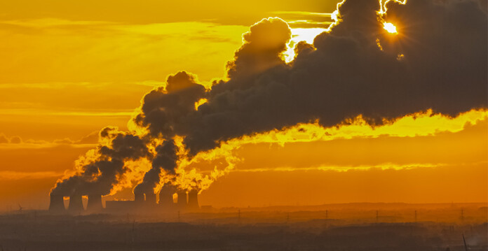 Carbon emissions pouring into hazy orange sky from industrial skyline (sequestration)
