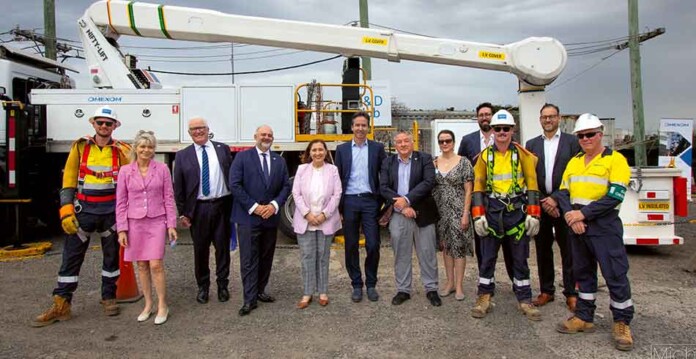 Ministers, executives and officials pose for photo in front of crane truck at facility