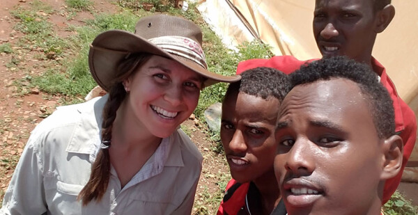 Woman smiling with group of young men in Ethiopian refugee camp