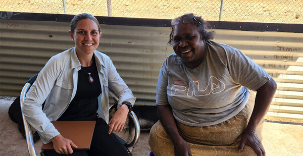 Two First Nations women seated in chairs smiling for photo