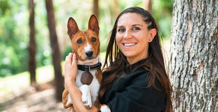 Young woman holding a cute dog in forested area
